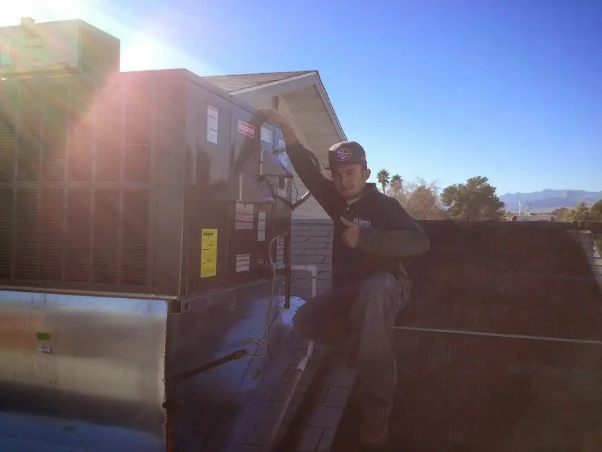 HVAC technician performing HVAC Inspection on a rooftop unit in Mashpee